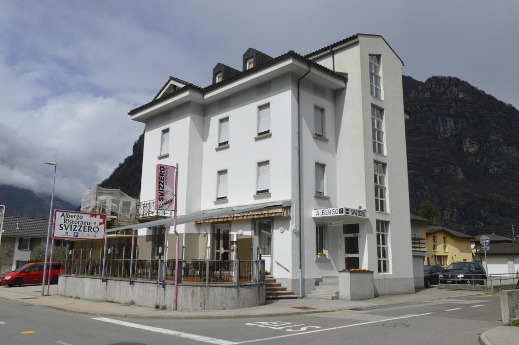 a white building on the corner of a street at Albergo Svizzero in Biasca