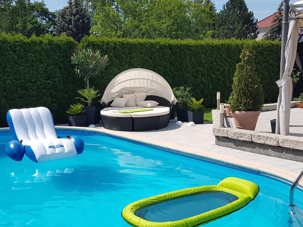 a pool with two chairs and a bed in a backyard at Gästezimmer im bewohnten EFH mit Pool und Garten in Ziltendorf