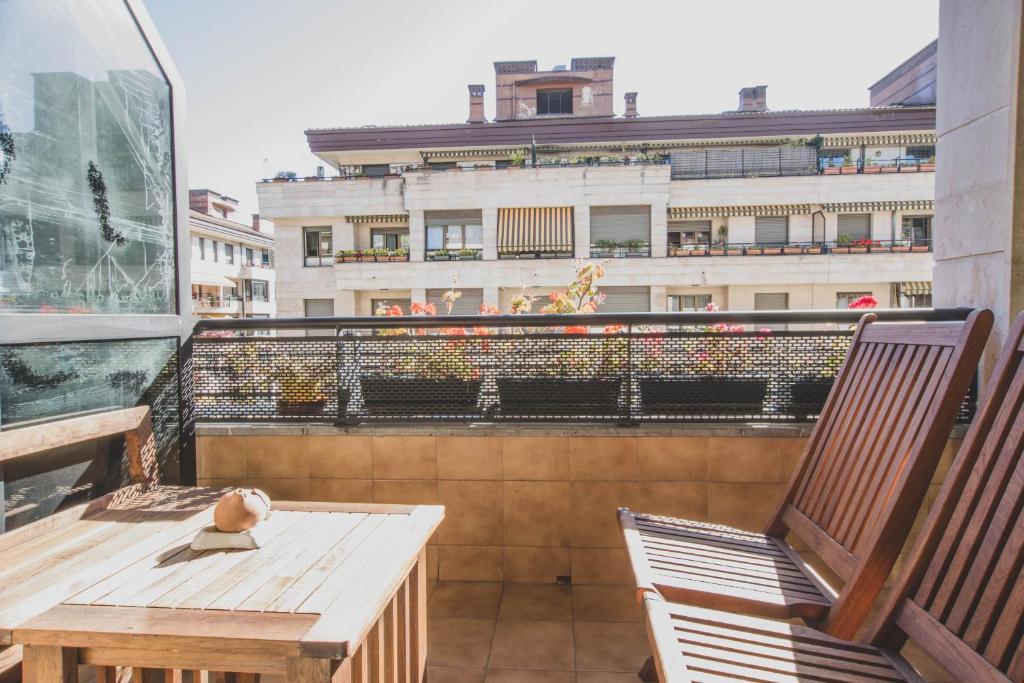 a balcony with a wooden table and chairs and a building at Arriola - Local Rentss in San Sebastián