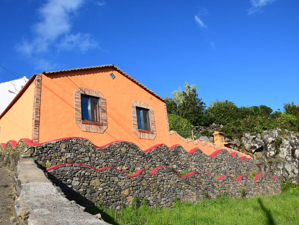 una casa naranja en la parte superior de una pared de piedra en Casa Boa Onda, en Lajes das Flores