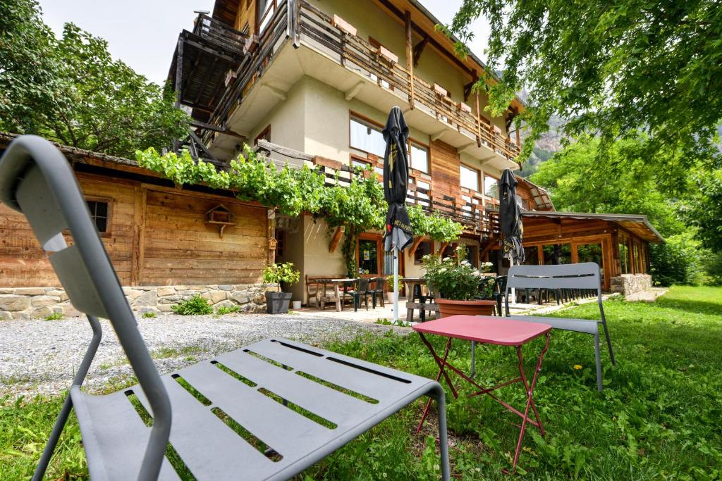 um banco e uma cadeira em frente a uma casa em Hôtel Restaurant Gîtes Les 5 Saisons em Freissinieres