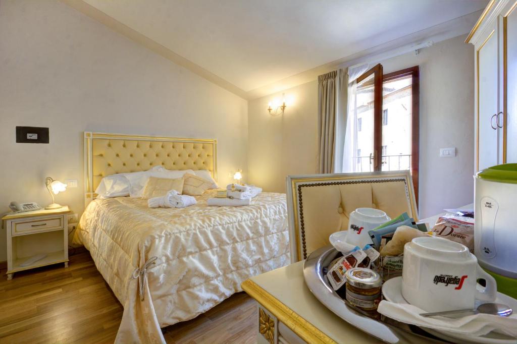 a bedroom with a bed and a table with a tray of dishes at Hotel Volterra In in Volterra
