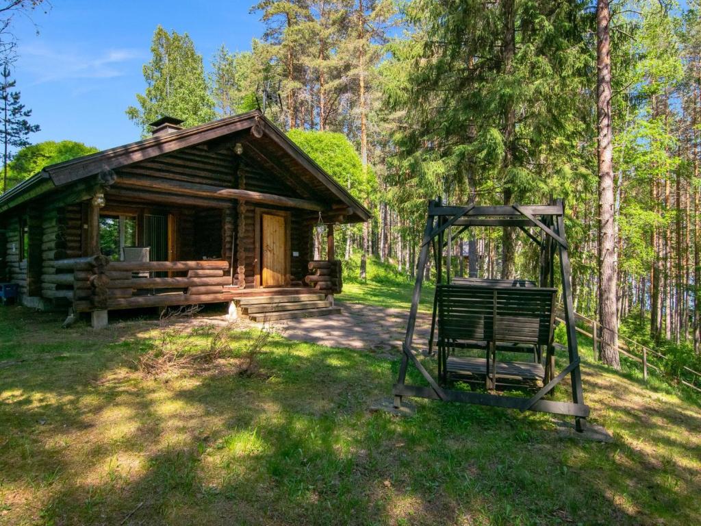 una cabaña de madera en el bosque con un columpio en Holiday Home Oravanpesä by Interhome en Tuohikotti