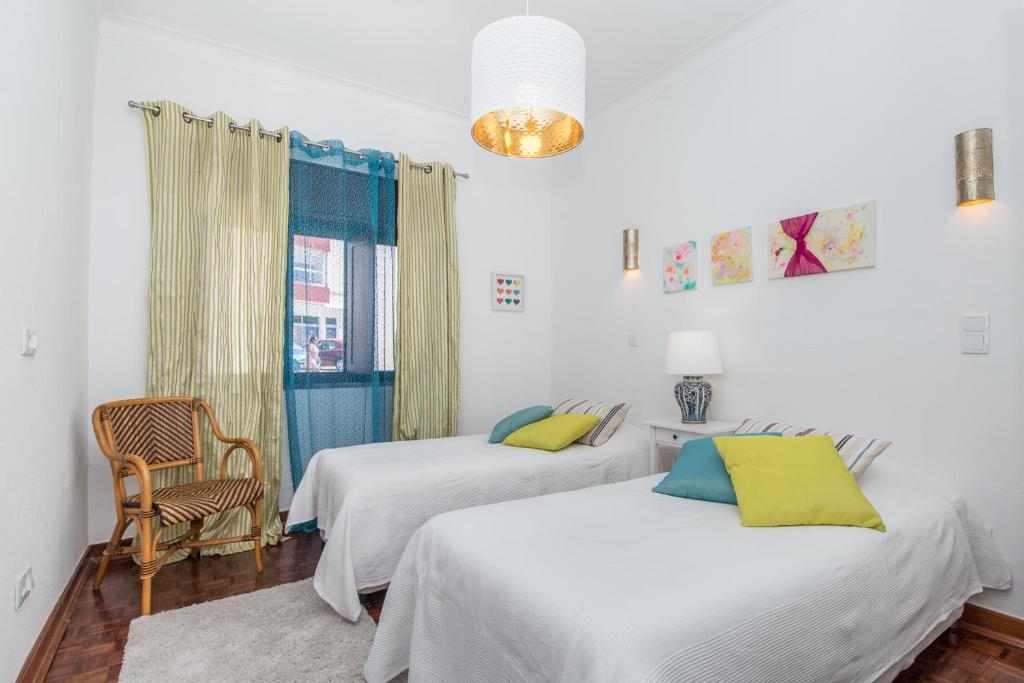 Un dormitorio con dos camas y una silla y una ventana. en Casa Jacarandá, en Silves