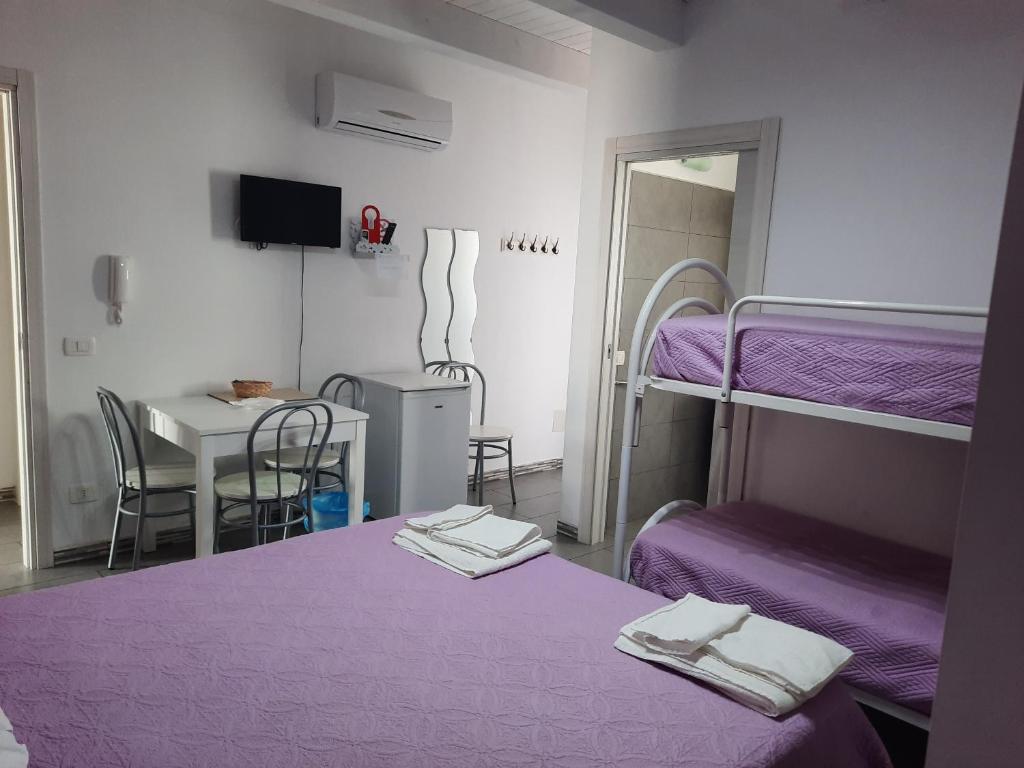 スコリッティにあるIttiturismo L'Ancoraの紫のシーツとテーブルが備わるベッド2台が備わる客室です。