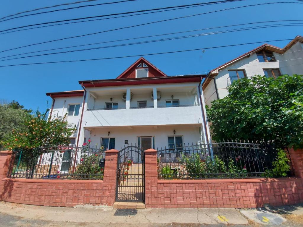 a white house with a red brick fence at Casa Atlas in Eforie Sud