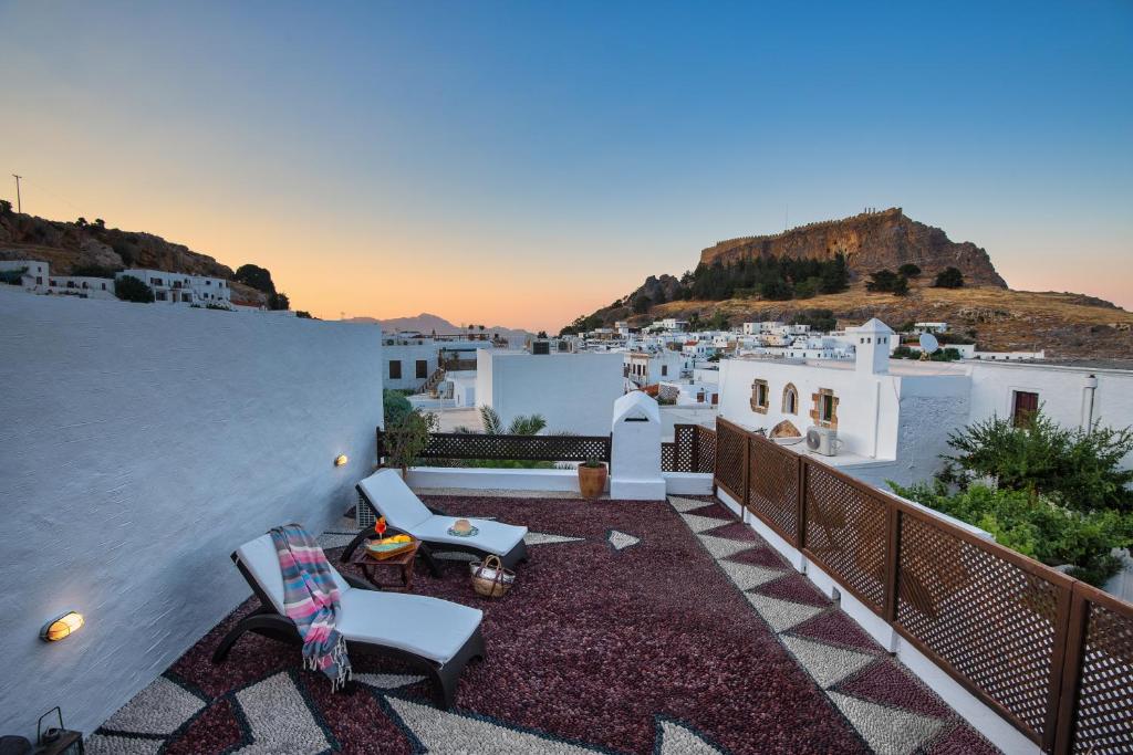 a balcony with chairs and a view of a city at Antique Villa in Líndos