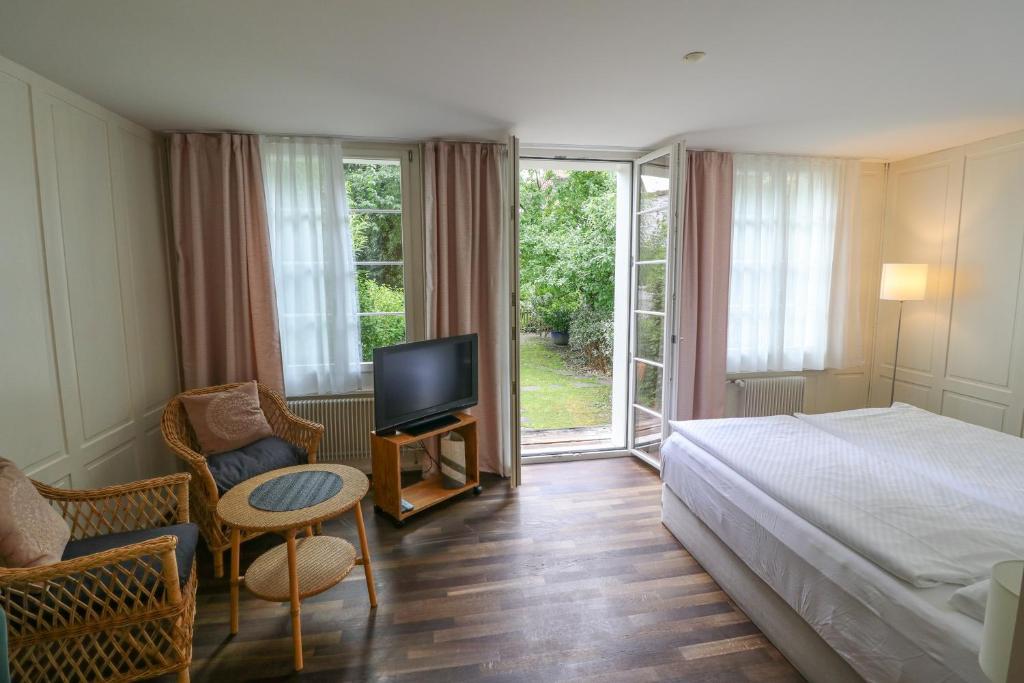 Schlafzimmer mit einem Bett, einem TV und einem Stuhl in der Unterkunft EMMA Bett und Bistro in Winterthur