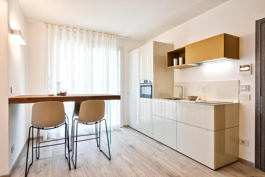 a kitchen with white cabinets and a bar with stools at Albamarina Residence in Sottomarina