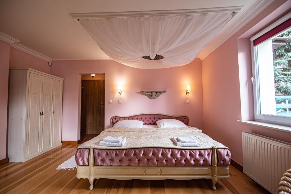 a bedroom with a bed with pink walls and a window at HydroZagadka Kołobrzeg in Kołobrzeg