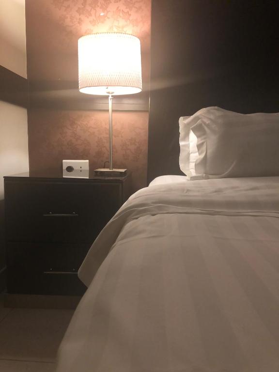 Hotel شقق بيت الوهد للشقق المخدومة, a bedroom with a white bed and a lamp at شقق بيت الوهد للشقق المخدومة in Riyadh