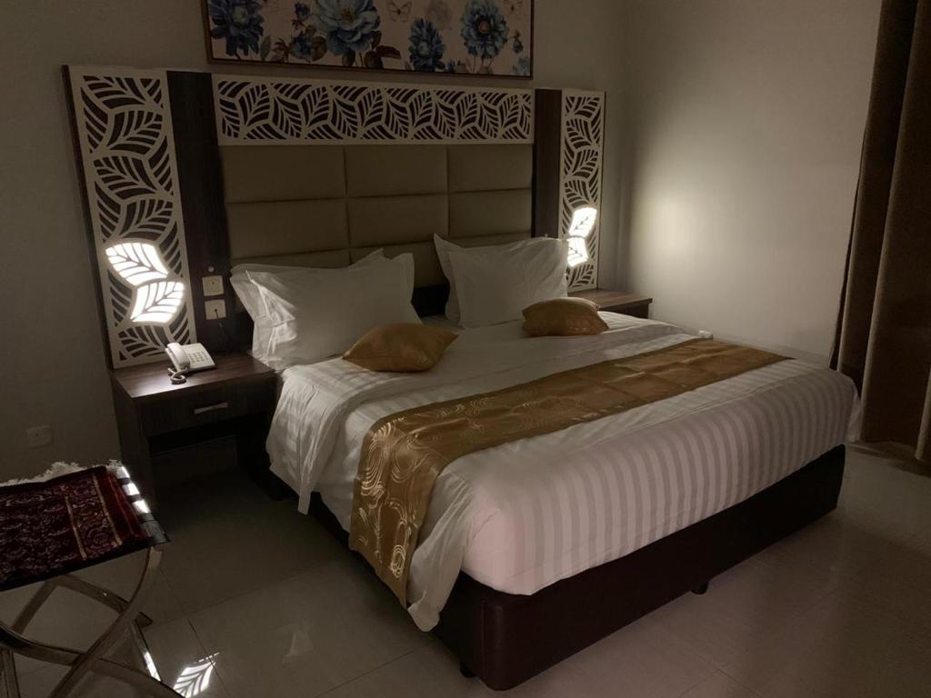 een slaapkamer met een groot bed met 2 lampen erop bij Manazelna Aparthotel in Jeddah