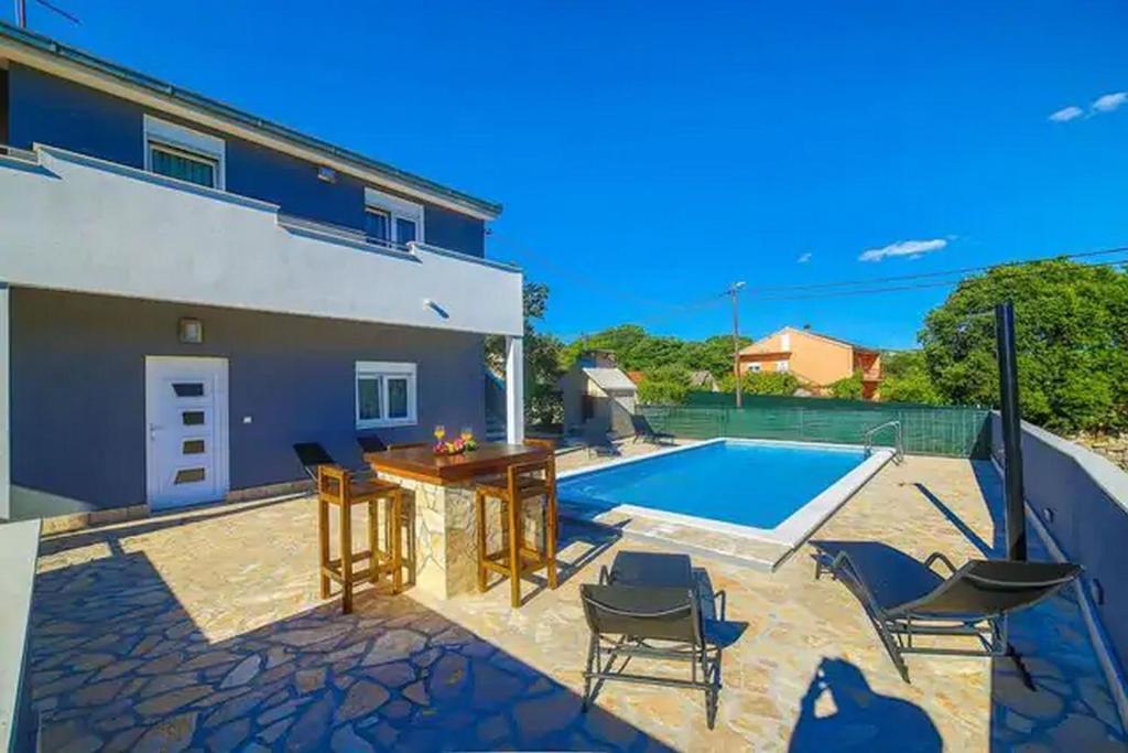 eine Terrasse mit einem Pool und Stühlen sowie ein Haus in der Unterkunft Holiday Home Zen in Primorski Dolac