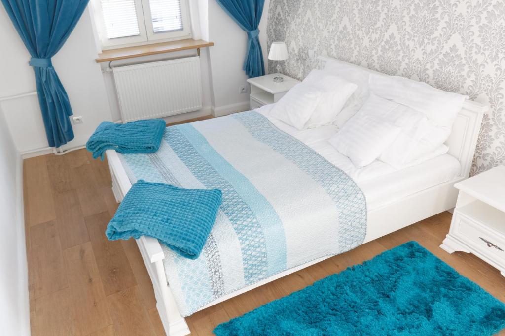 a bedroom with a white bed with blue rugs at Apartamenty Hexus - Świdnicka - Wrocław centrum Rynek in Wrocław