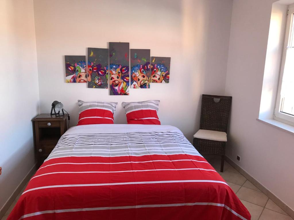 a bedroom with a red and white bed with two red pillows at Maison de village in Laubach