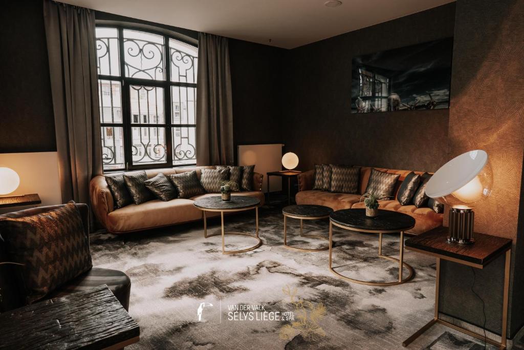 a living room with a couch and two tables at Van Der Valk Sélys Liège Hotel &amp; Spa in Liège