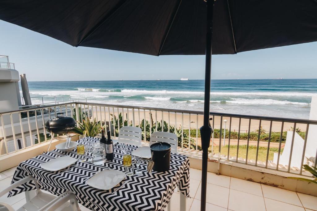 a table and chairs on a balcony with the beach at 9 Bronze Bay in Durban