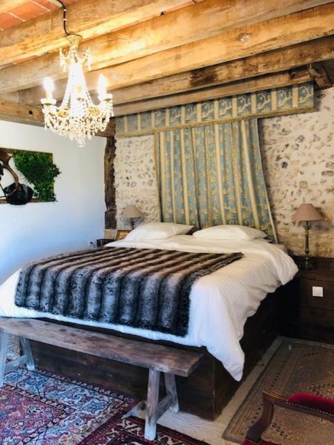 une chambre avec un grand lit avec un mur en bois dans l'établissement Chambre du parc Élevage Girbal, à La Chapelotte
