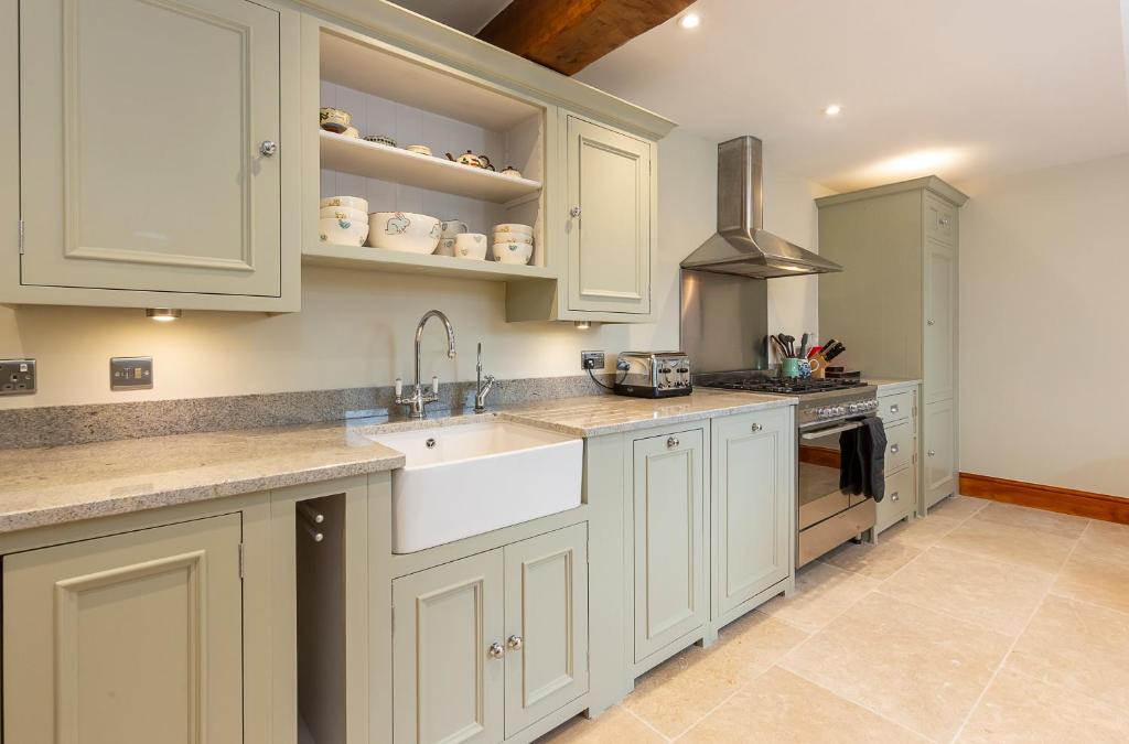 een keuken met witte kasten en een wastafel bij Creamery Cottage in York