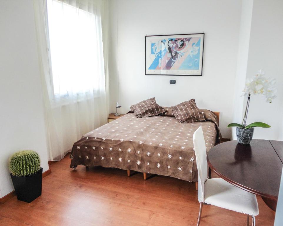 um quarto com uma cama, uma mesa e uma janela em Alloggio Cavour em Ferrara