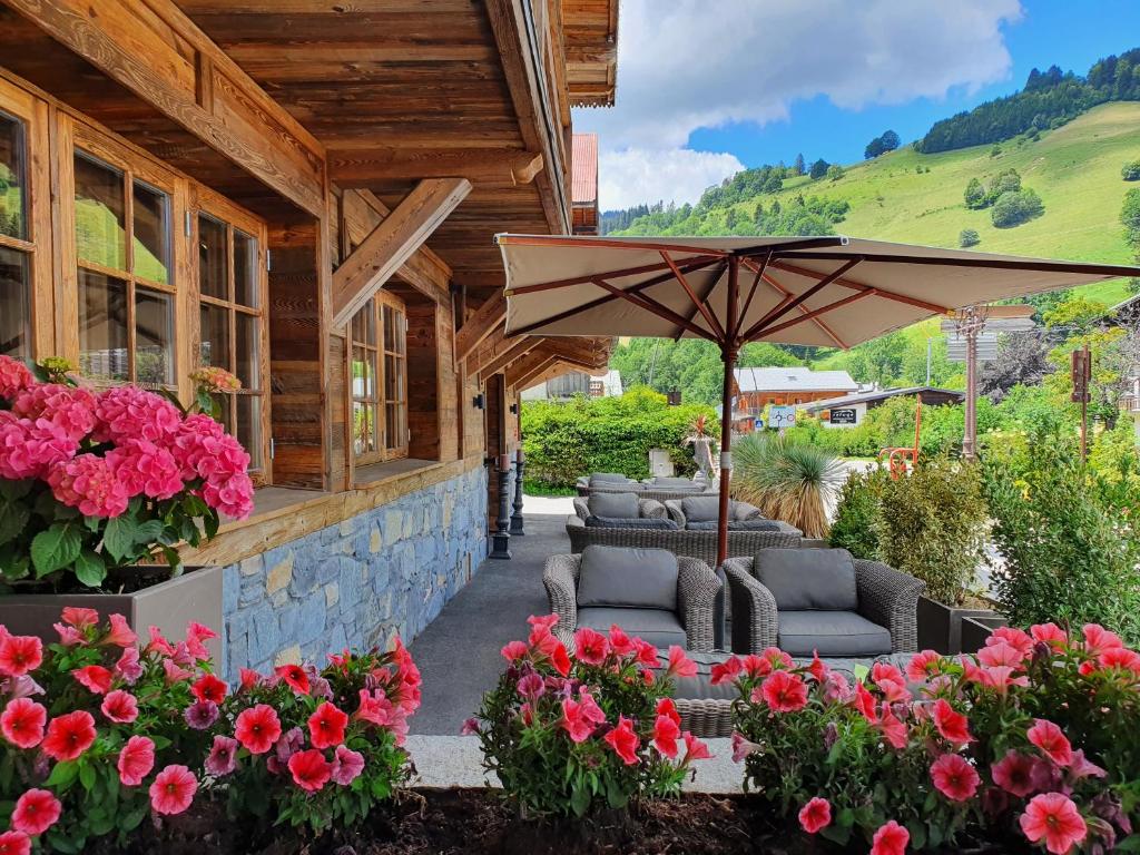 eine Terrasse mit Stühlen, einem Sonnenschirm und Blumen in der Unterkunft Le Chalet Blanc in Megève