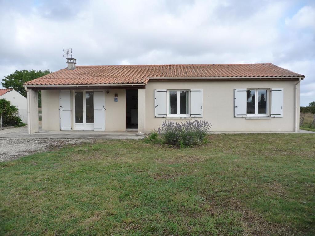 une maison blanche avec des fenêtres blanches et une cour dans l'établissement le marais, à LʼÉguille