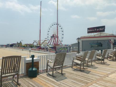 a group of chairs on a boardwalk with a ferris wheel at Atlantic Hotel, Inc in Ocean City