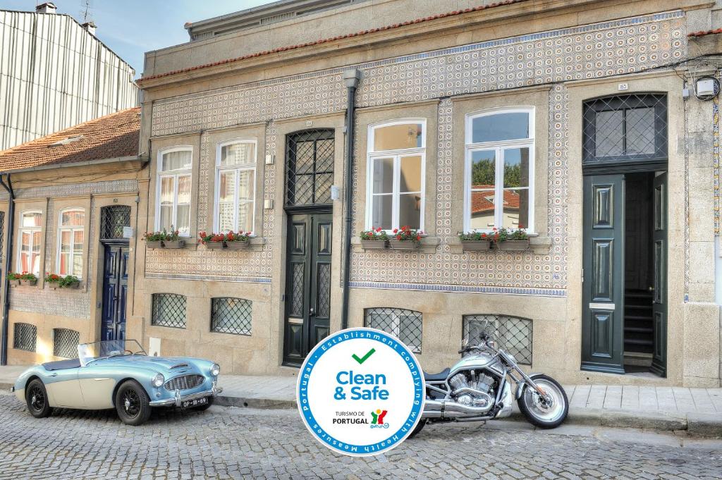 ein Auto und ein Motorrad, das vor einem Gebäude geparkt ist in der Unterkunft Three Houses & Bedrooms in Porto