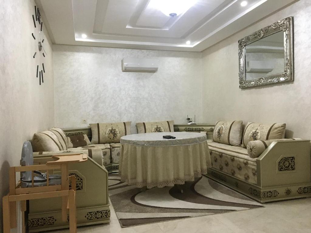 uma sala de estar com sofás, uma mesa e um espelho em Apartment Anis Nador Al Jadid em Nador