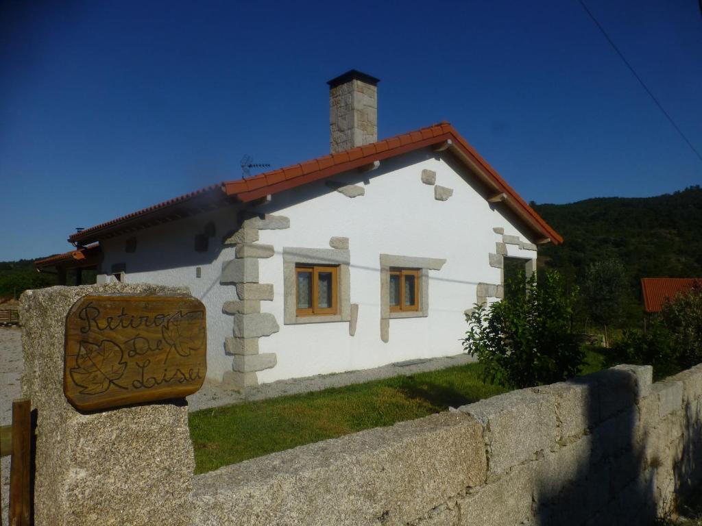 ein kleines weißes Haus hinter einer Steinmauer in der Unterkunft Casa Retiro de Lisei in Penalva do Castelo