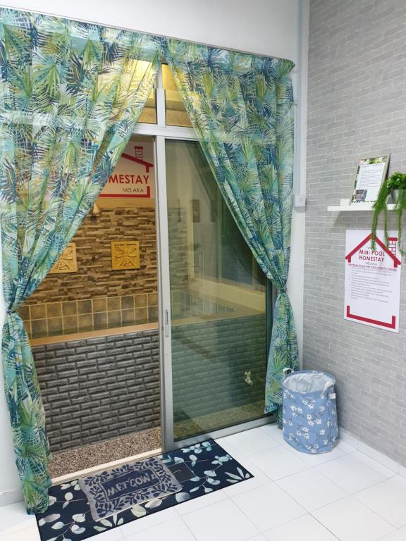 a glass door with a curtain in front of a building at Teratak Mini Pool Homestay Melaka in Melaka