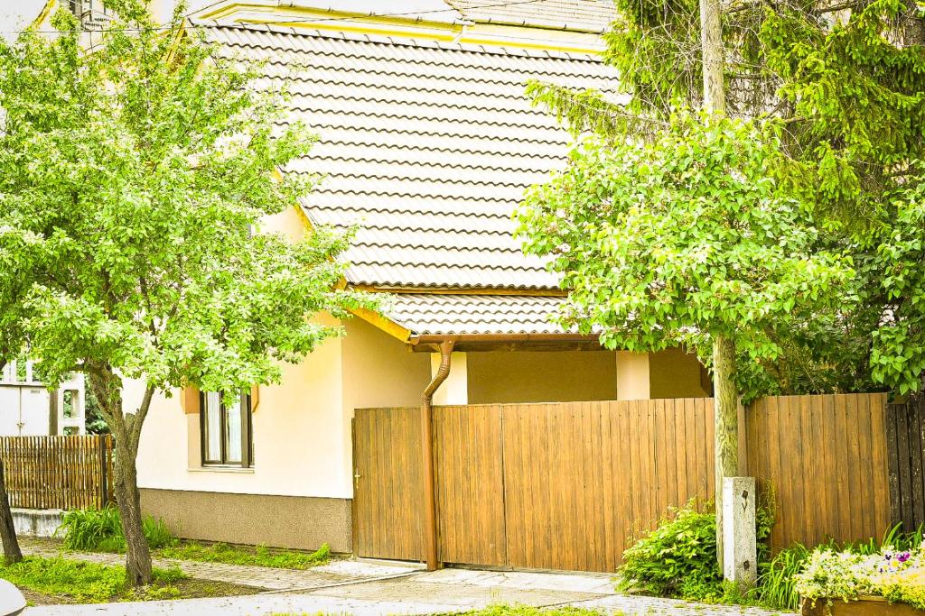 een huis met een hek en bomen ervoor bij Bárdos Vendégház in Tiszabábolna