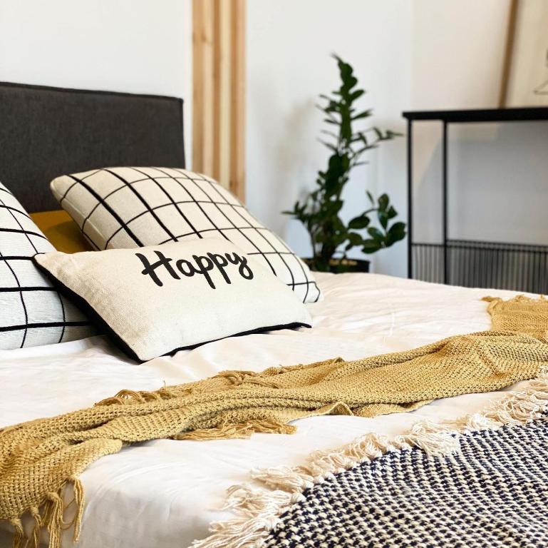 a bed with a happy pillow on top of it at Apartament Happy Loft MF in Giżycko