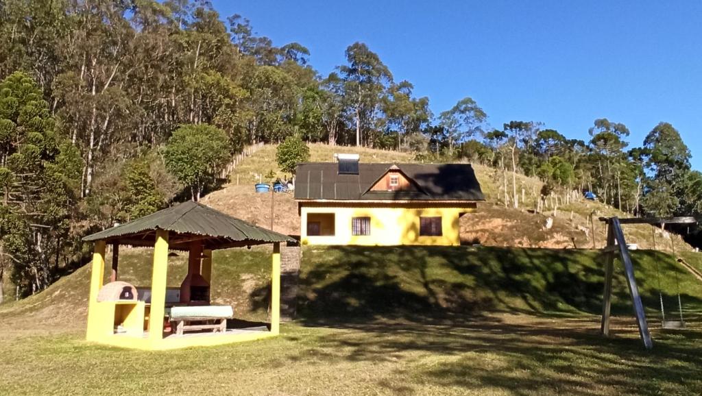 una casa en la cima de una colina con un parque infantil en Chalé em Delfim Moreira-MG, en Delfim Moreira