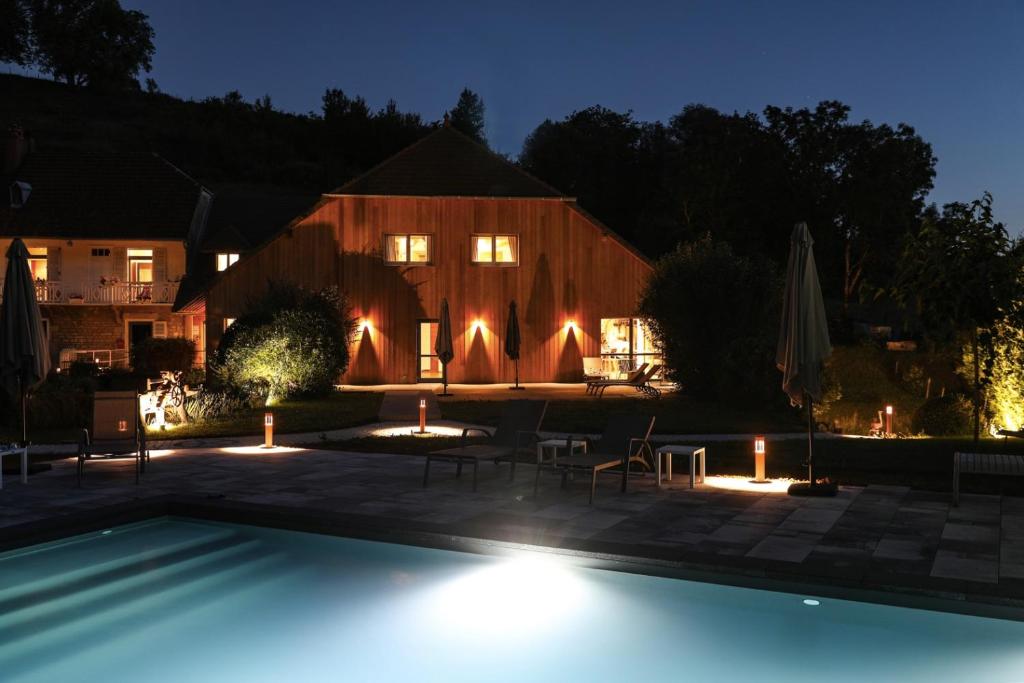 - une piscine en face d'une maison la nuit dans l'établissement Maison d'hôtes & SPA La Scierie, à Salins-les-Bains