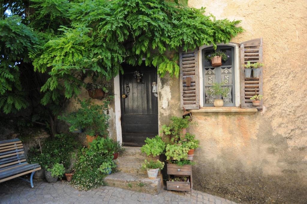 una casa con una porta e una finestra e piante in vaso di Appartement dans le ciel a Tourtour