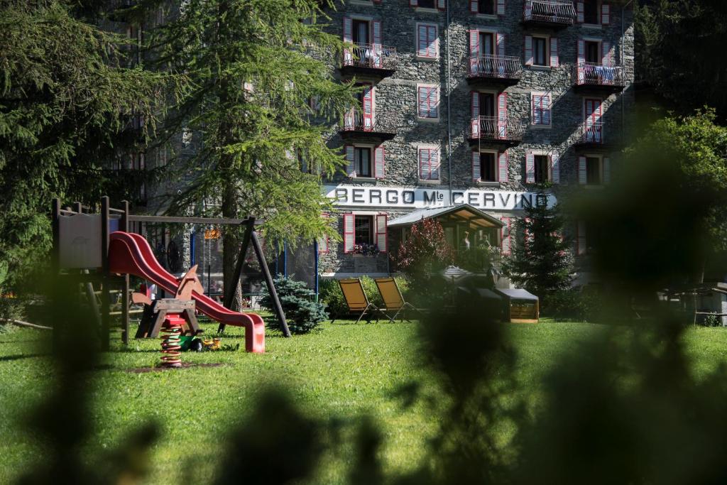 a playground in a park in front of a building at Albergo Monte Cervino in Champoluc