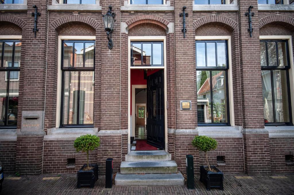 un edificio de ladrillo con puerta roja y ventanas en Oude Postkantoor de Rijp, en De Rijp