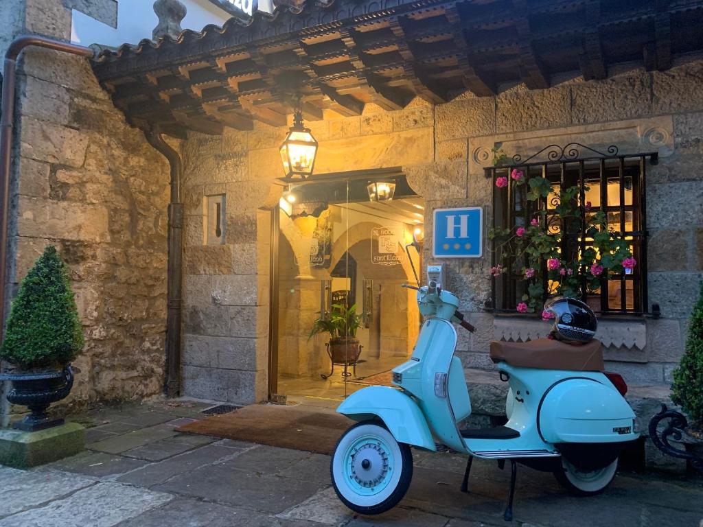 a blue scooter parked in front of a building at Hotel Santillana in Santillana del Mar