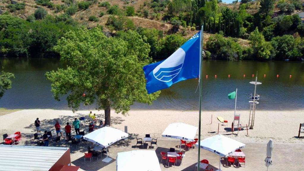 a blue flag on a beach next to a lake at Apartamento Trav. Santa Luzia in Mirandela