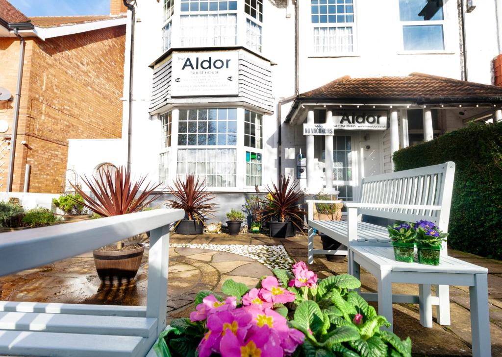 un patio con 2 bancos y flores frente a un edificio en The Aldor, en Skegness