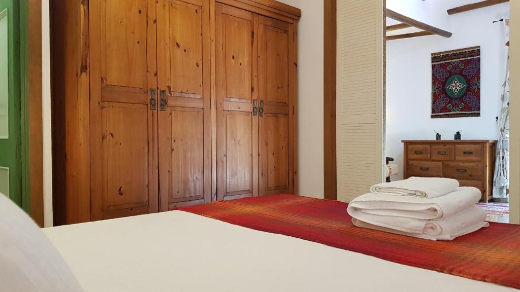 オルヒバにあるポサダ アルプハラ ソルのベッドルーム1室(ベッド1台、木製キャビネット、白いタオル付)