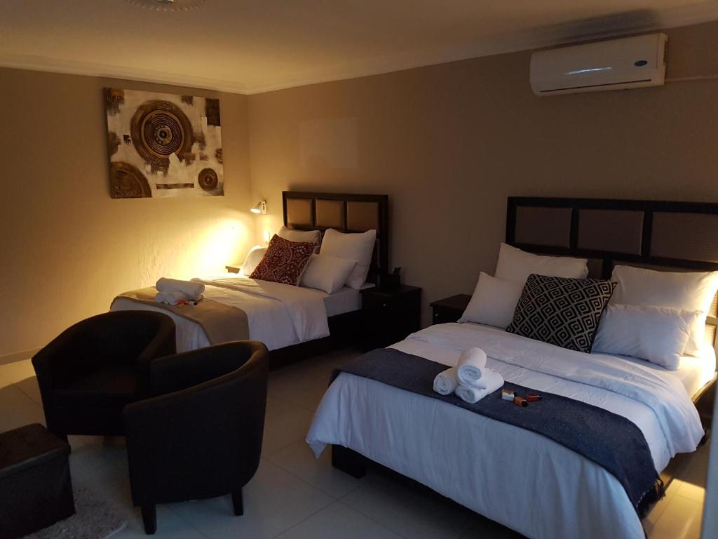 a hotel room with two beds and a chair at The Royal Prime Guest Lodge in Centurion