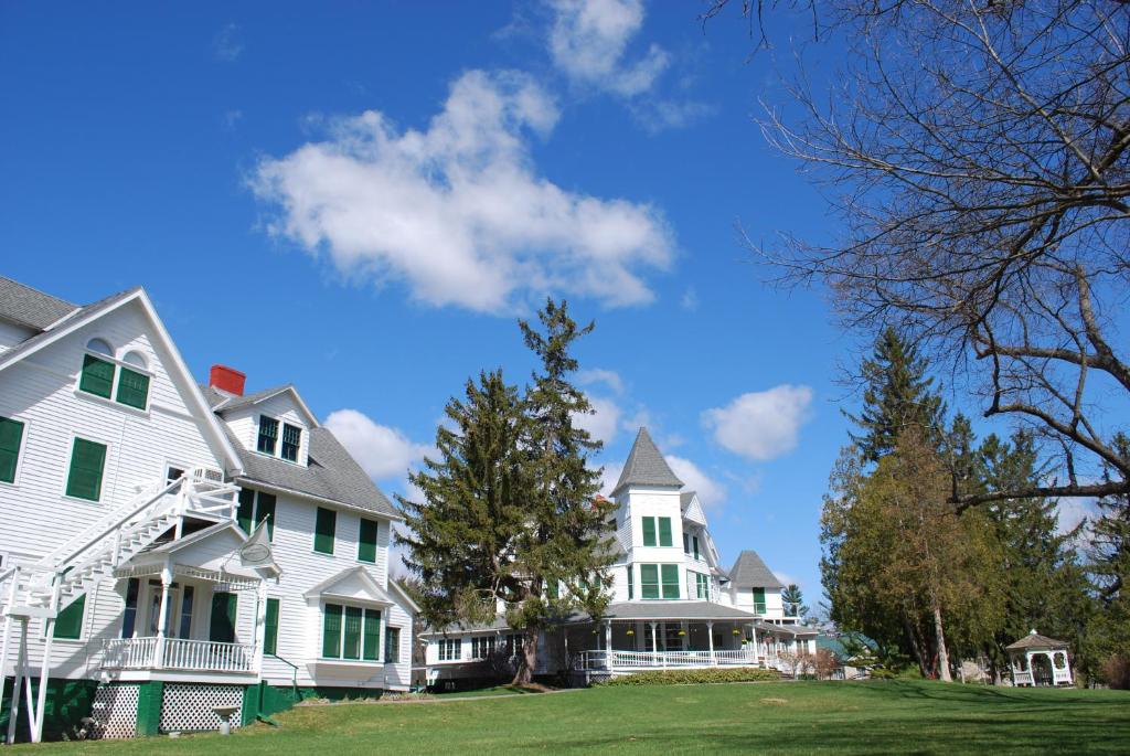 a large white house with green windows and trees at Anne's Washington Inn in Saratoga Springs