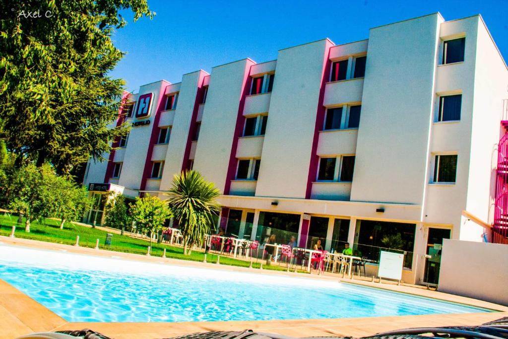 un hotel con piscina frente a un edificio en Best Western Hotelio Montpellier Sud, en Montpellier