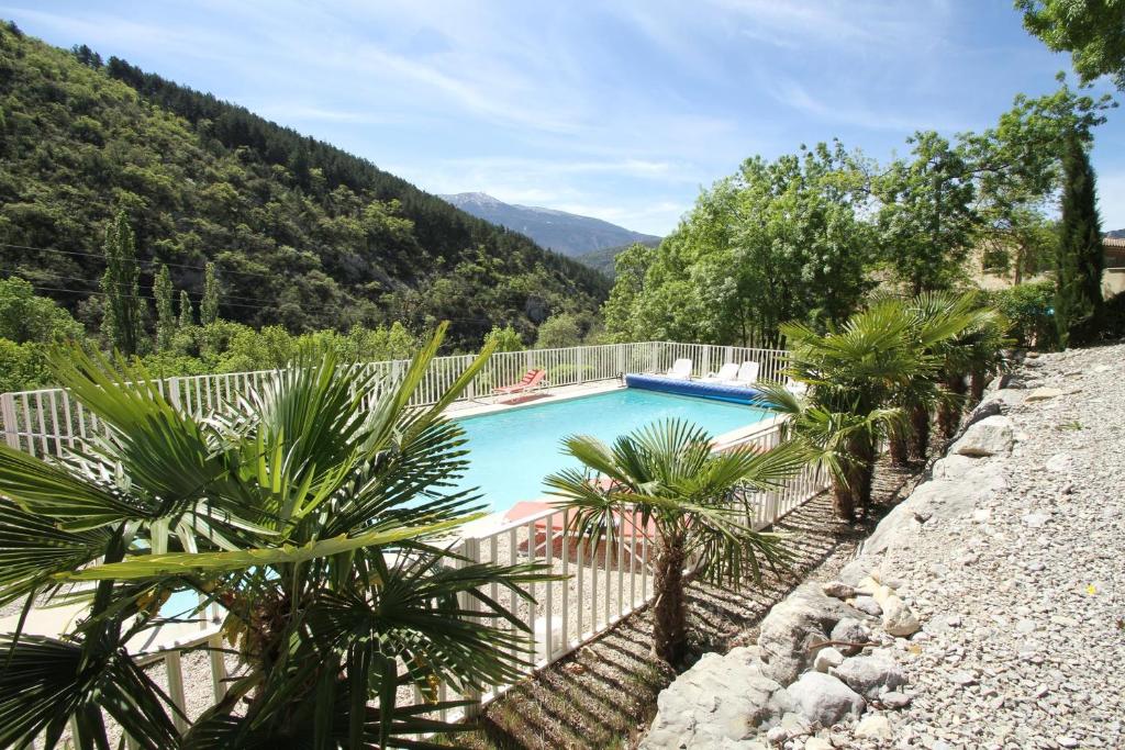 a swimming pool with palm trees next to a fence at LA BAPTISTINE FACE AU VENTOUX in Plaisians