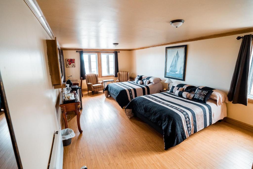 a bedroom with two beds and a table and chairs at Auberge du Vieux Faubourg in Sainte-Anne-des-Monts