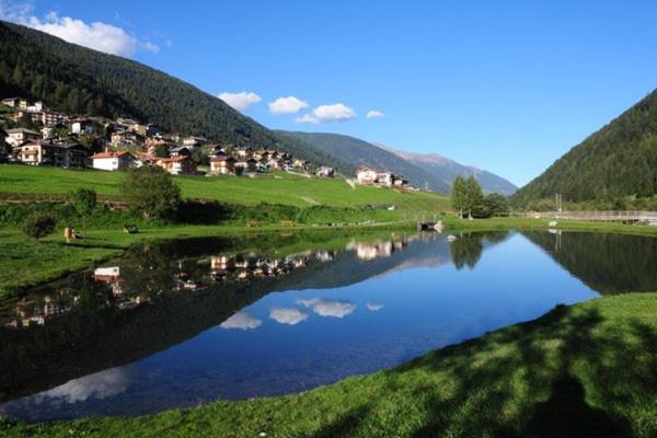 a body of water with houses and mountains in the background at Appartamento Ilaria in Vermiglio