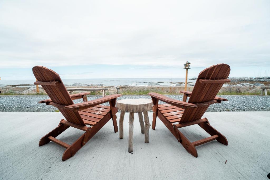 two wooden chairs and a table on a porch at Auberge du Vieux Faubourg in Sainte-Anne-des-Monts