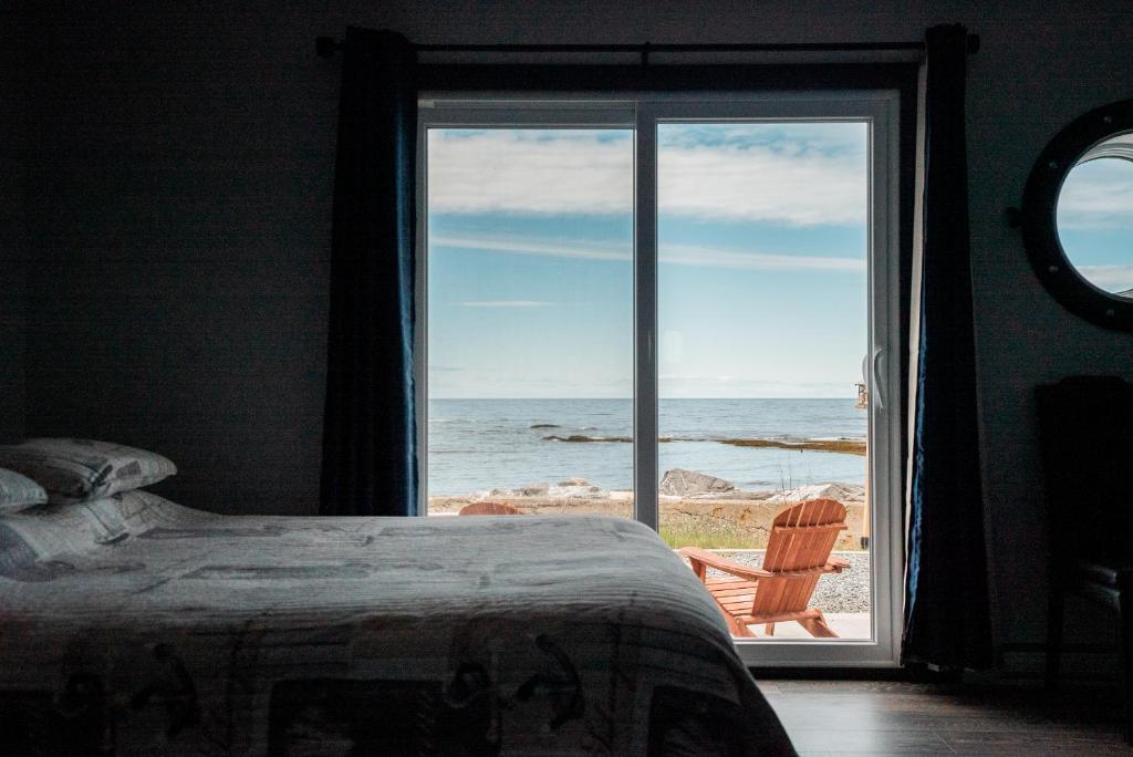 a bedroom with a bed and a view of the ocean at Auberge du Vieux Faubourg in Sainte-Anne-des-Monts
